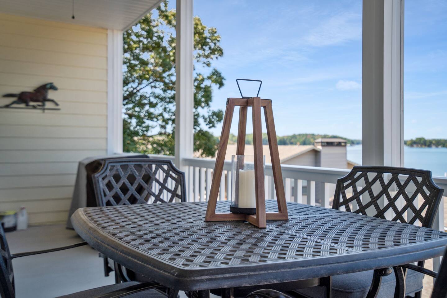 A table and chairs on a porch with a lantern on it.