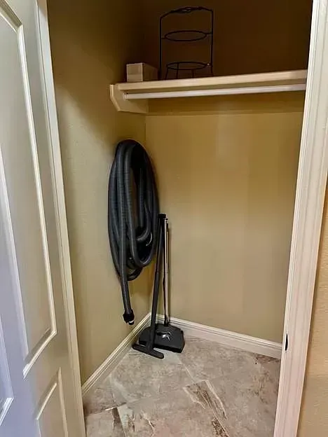 A closet with a vacuum cleaner and a hose hanging on the wall.