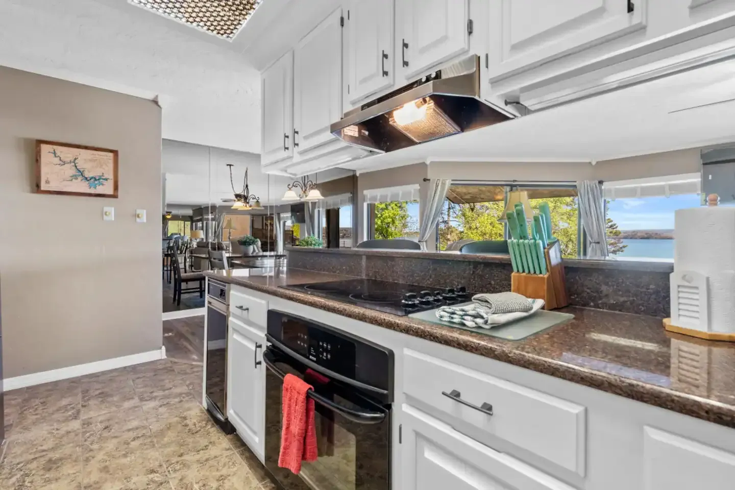 A kitchen with white cabinets , stainless steel appliances , granite counter tops and a stove top oven.