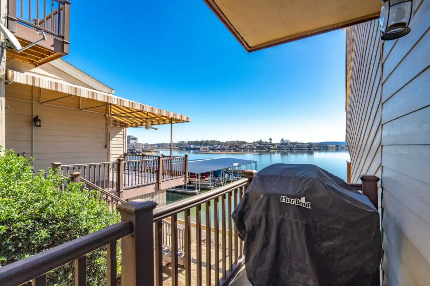 A grill is sitting on a balcony overlooking a body of water.