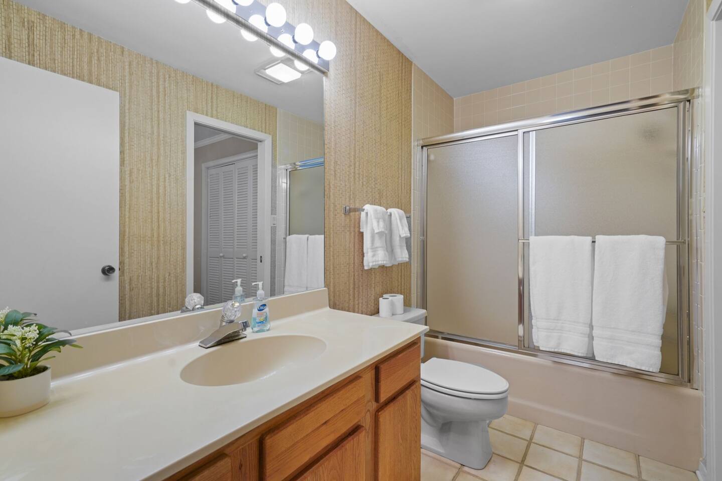 A bathroom with a sink , toilet , shower and mirror.