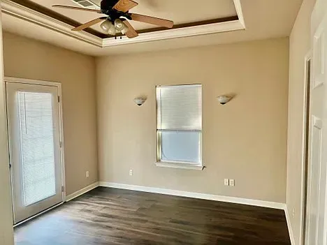 An empty room with a ceiling fan and a window.