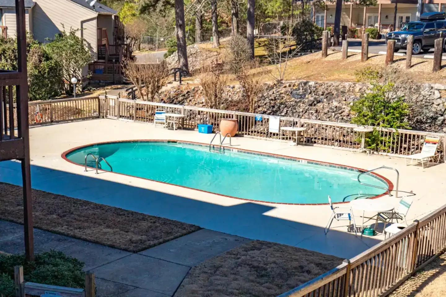 A large swimming pool is surrounded by a fence and chairs.
