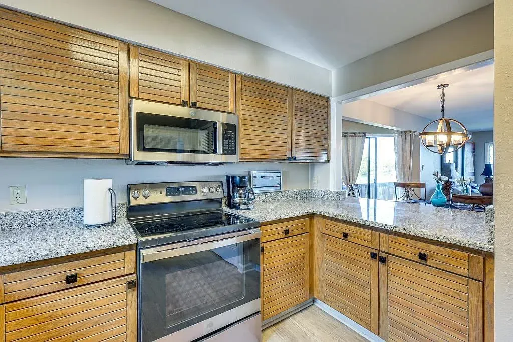A kitchen with a stove , oven , microwave and granite counter tops.