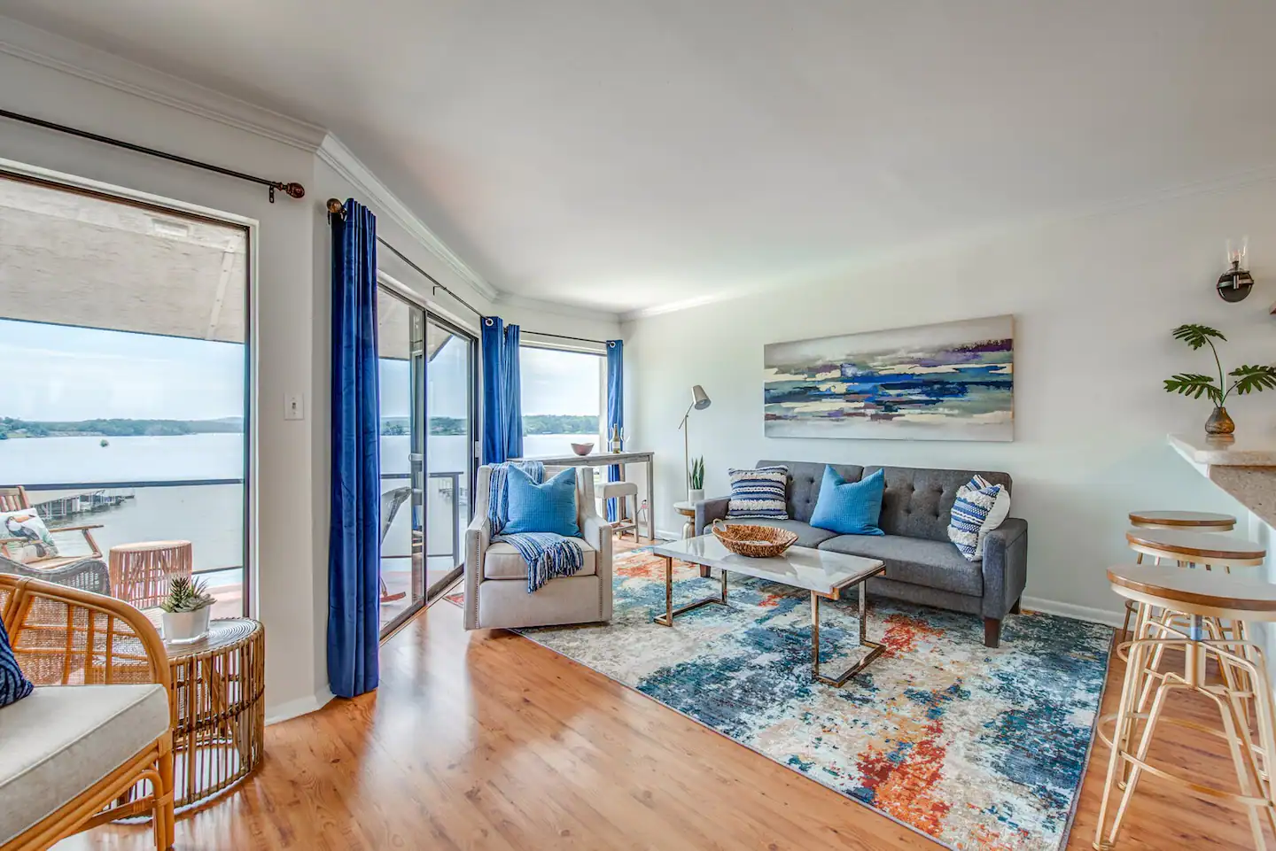 A living room with a couch , chairs , a table and a view of the water.