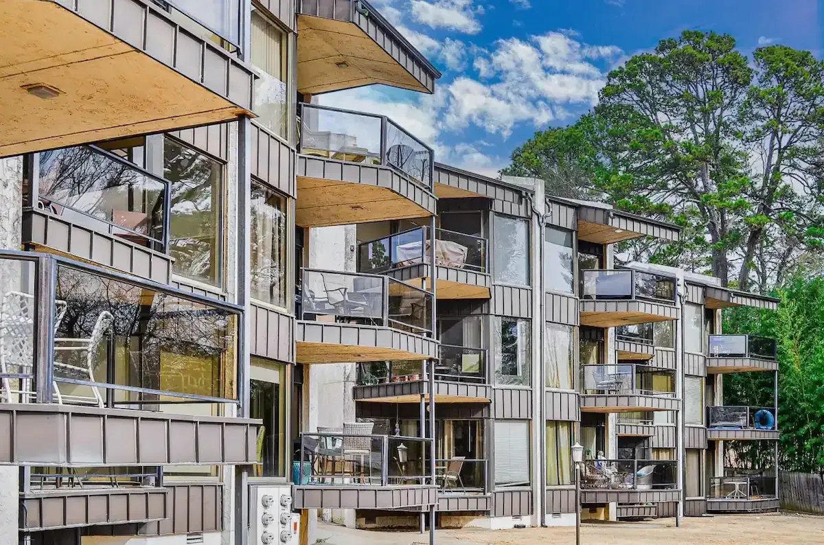 A row of apartment buildings with balconies and trees in the background.