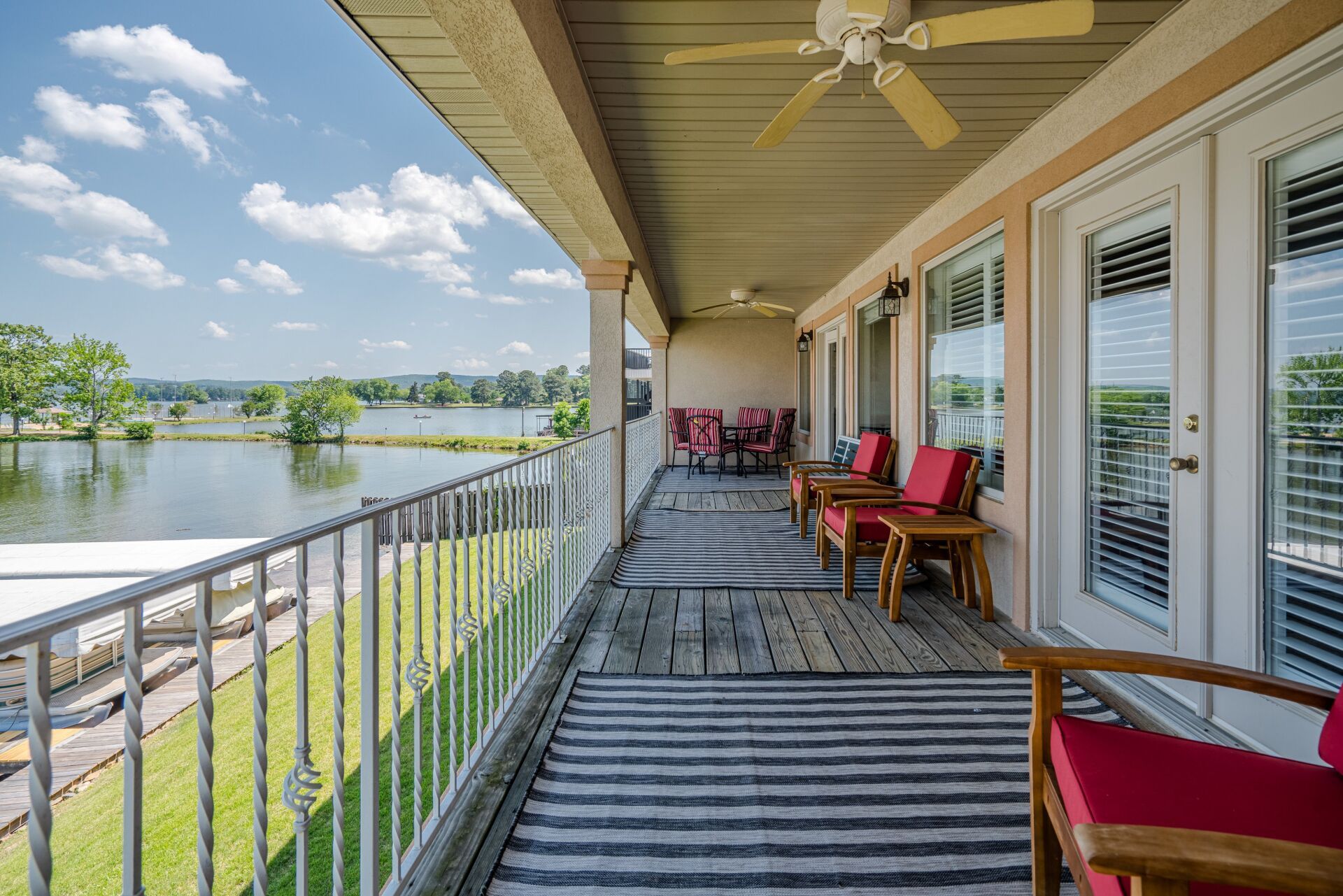 A large porch with a view of a lake and a ceiling fan.