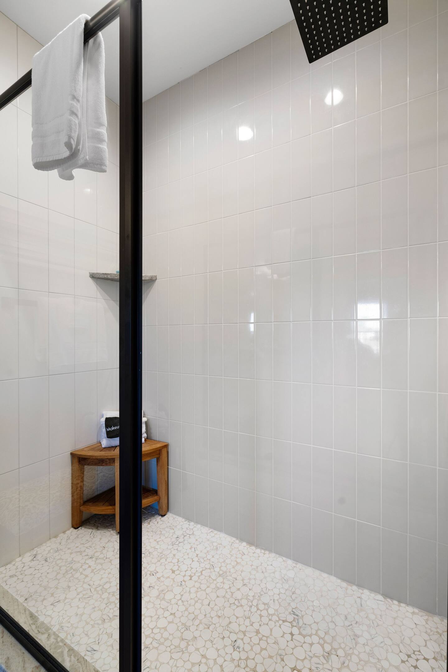 A bathroom with a walk in shower and a wooden bench.
