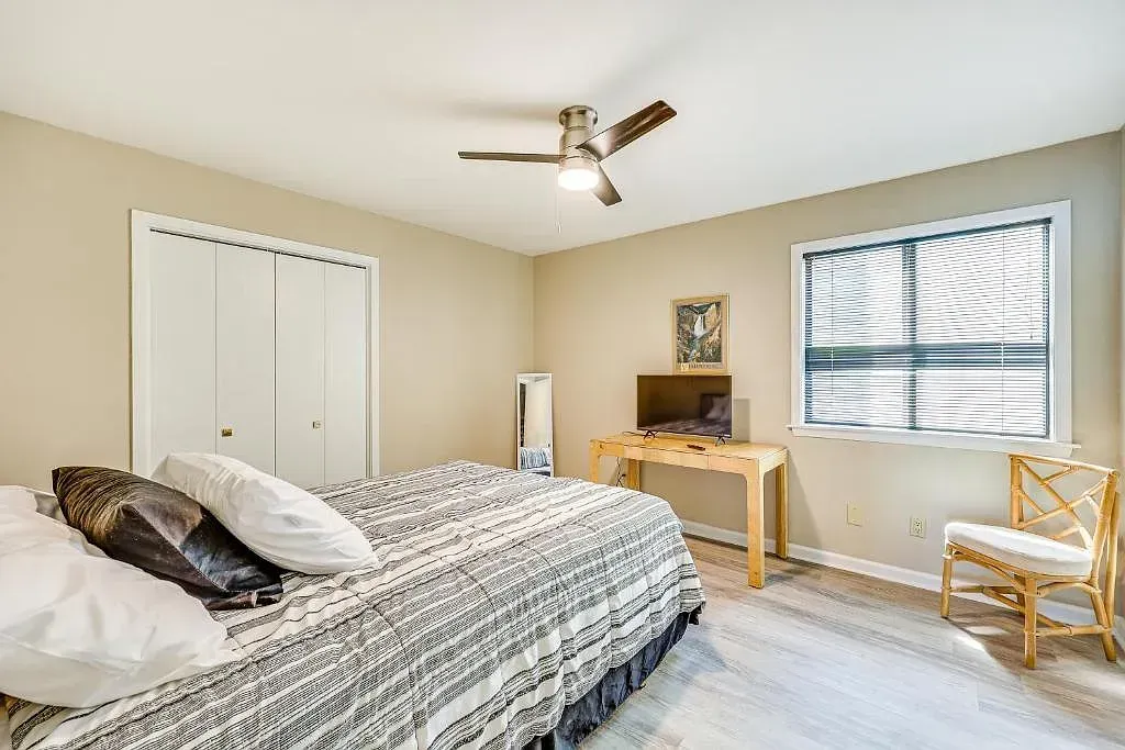 A bedroom with a bed , chair , desk and ceiling fan.
