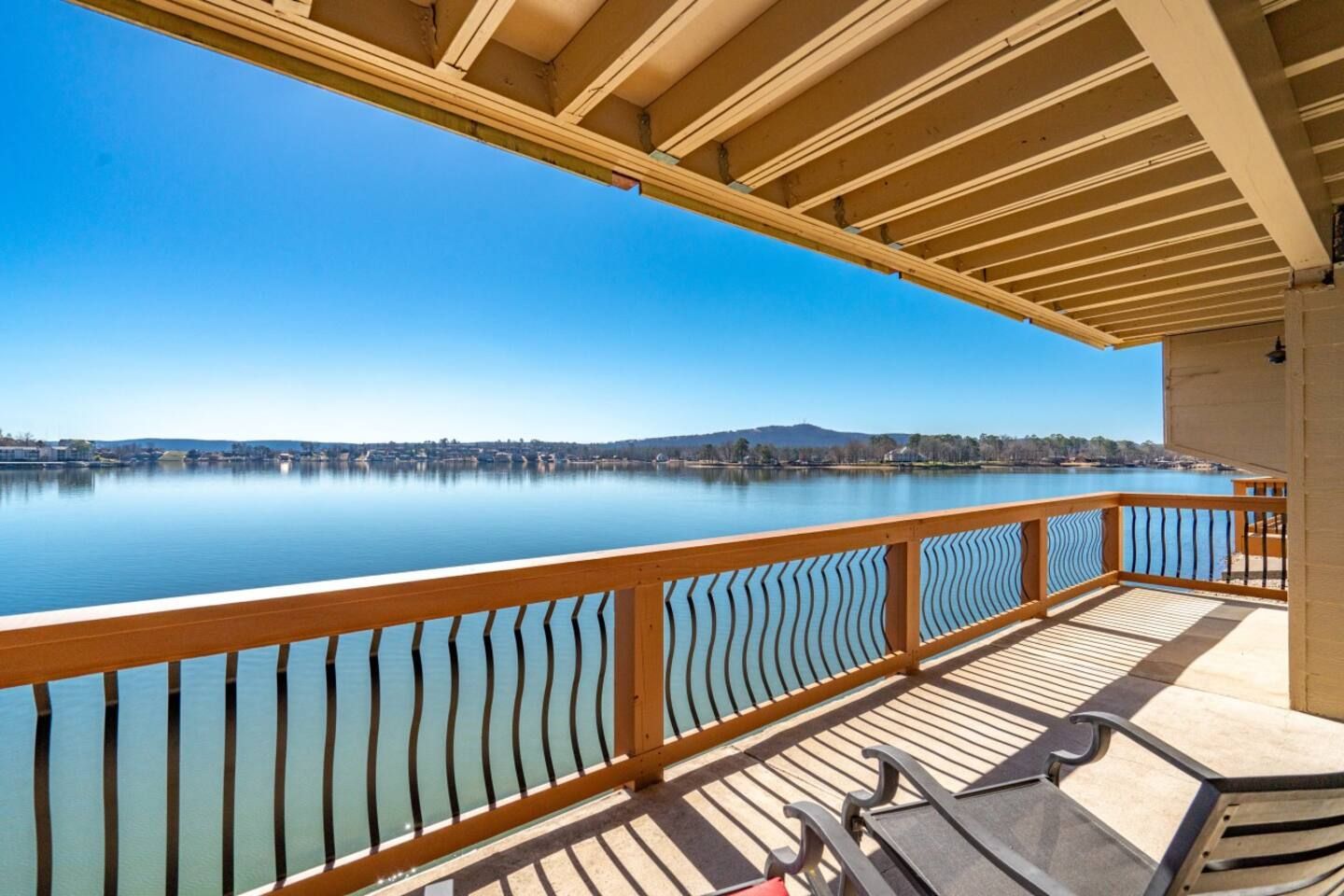 A balcony overlooking a body of water with a chair and table.