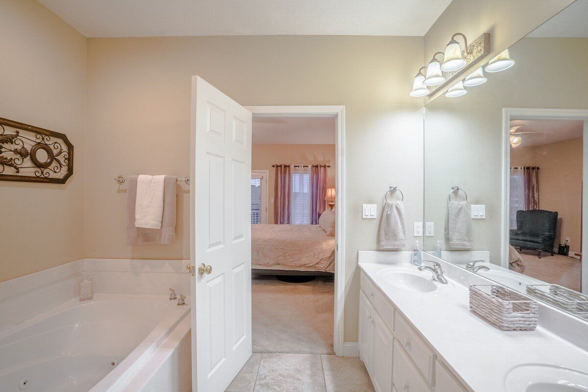 A bathroom with two sinks , a tub , and a mirror.