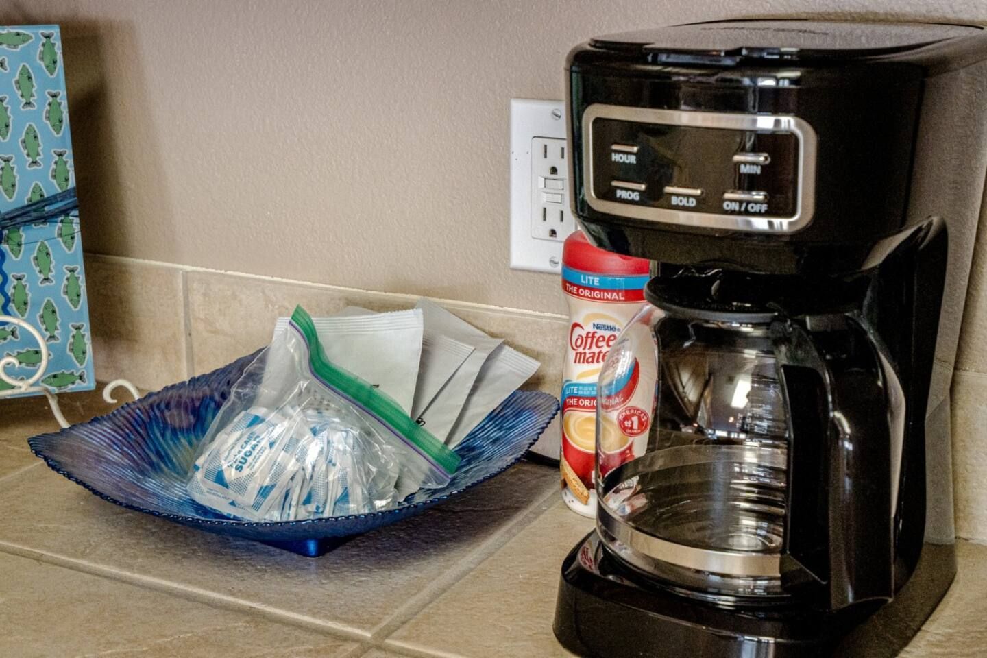A coffee maker is sitting on a counter next to a bowl of ice cubes.