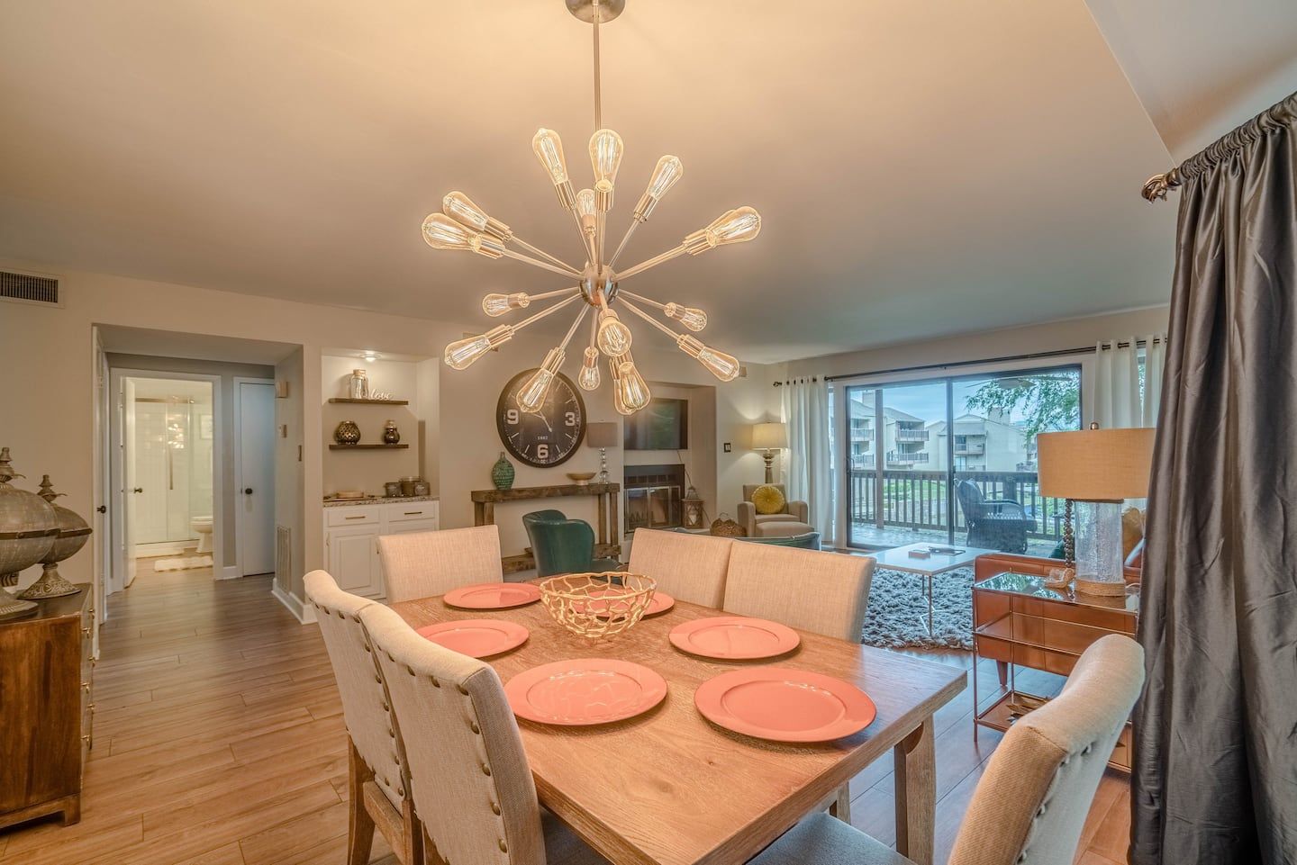A dining room with a wooden table and chairs and a chandelier hanging from the ceiling.