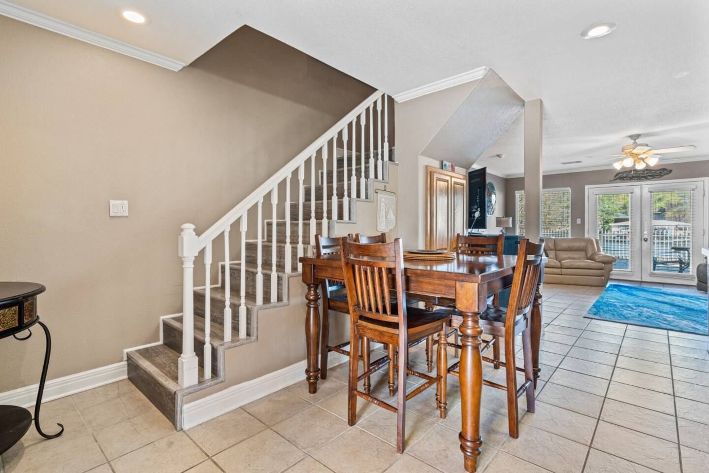 A dining room with a table and chairs and stairs leading up to the second floor.