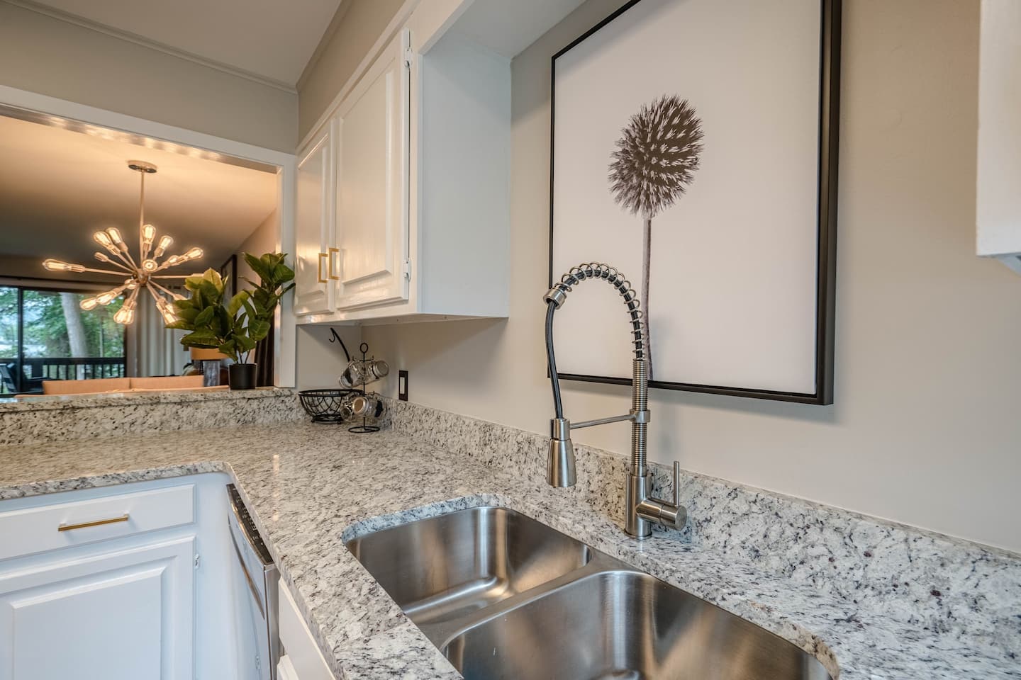 A kitchen with two sinks and a picture on the wall above the sink.