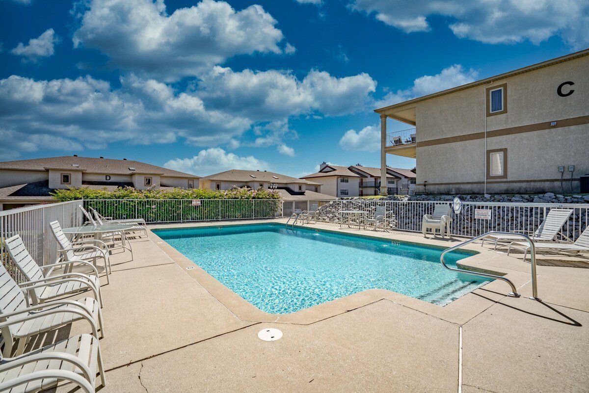 A large swimming pool is surrounded by chairs and a building.