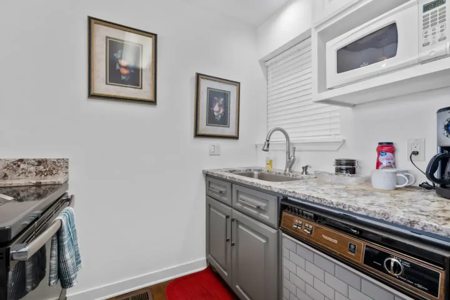 A kitchen with a sink , stove , microwave and dishwasher.