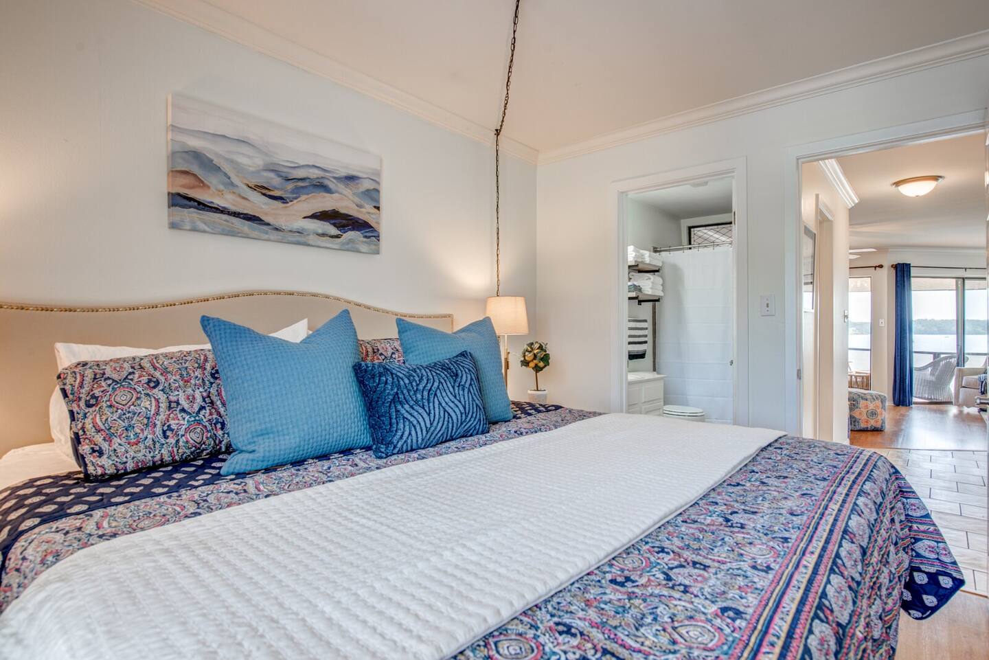 A bedroom with a king size bed and blue and white pillows.
