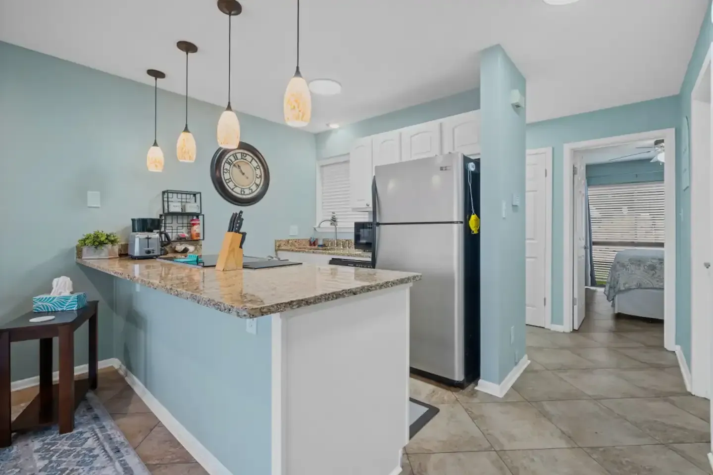 A kitchen with a stainless steel refrigerator and a granite counter top.