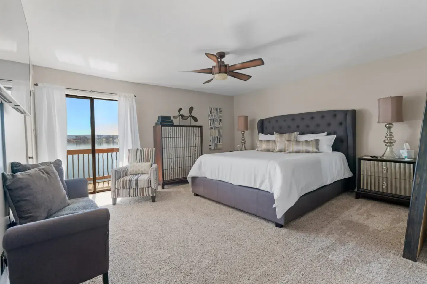 A bedroom with a king size bed , a couch , and a ceiling fan.