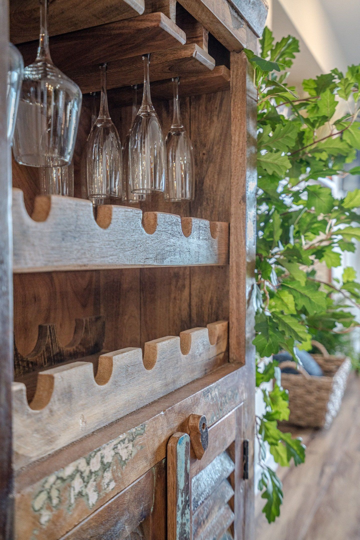 A wooden wine rack with wine glasses hanging from it.