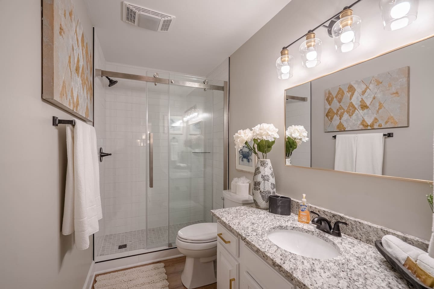 A bathroom with a sink , toilet , shower and mirror.