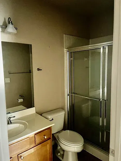 A bathroom with a toilet , sink and shower.