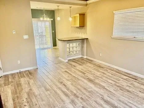 An empty living room with hardwood floors and a window.