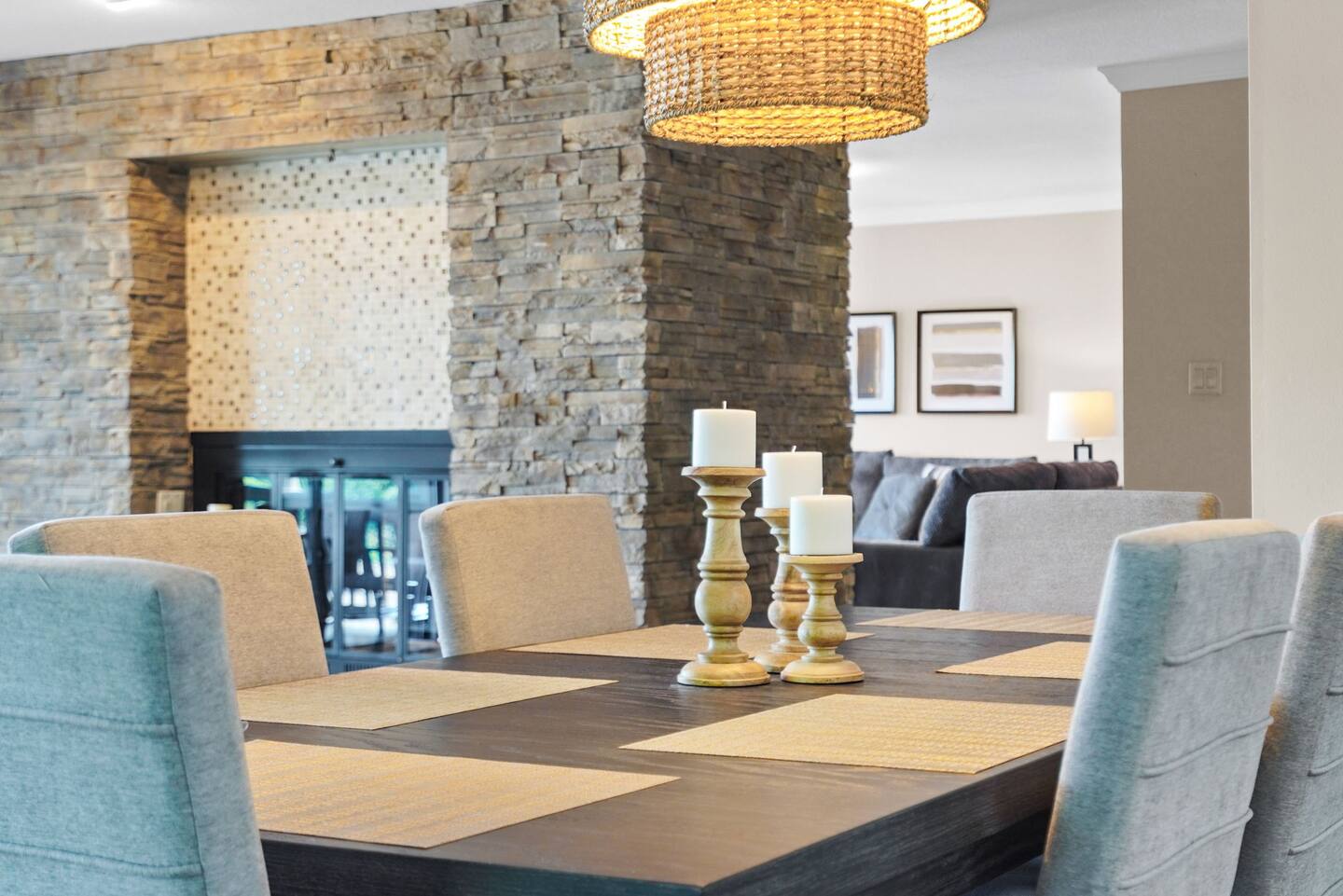 A dining room table with candles on it and a fireplace in the background.