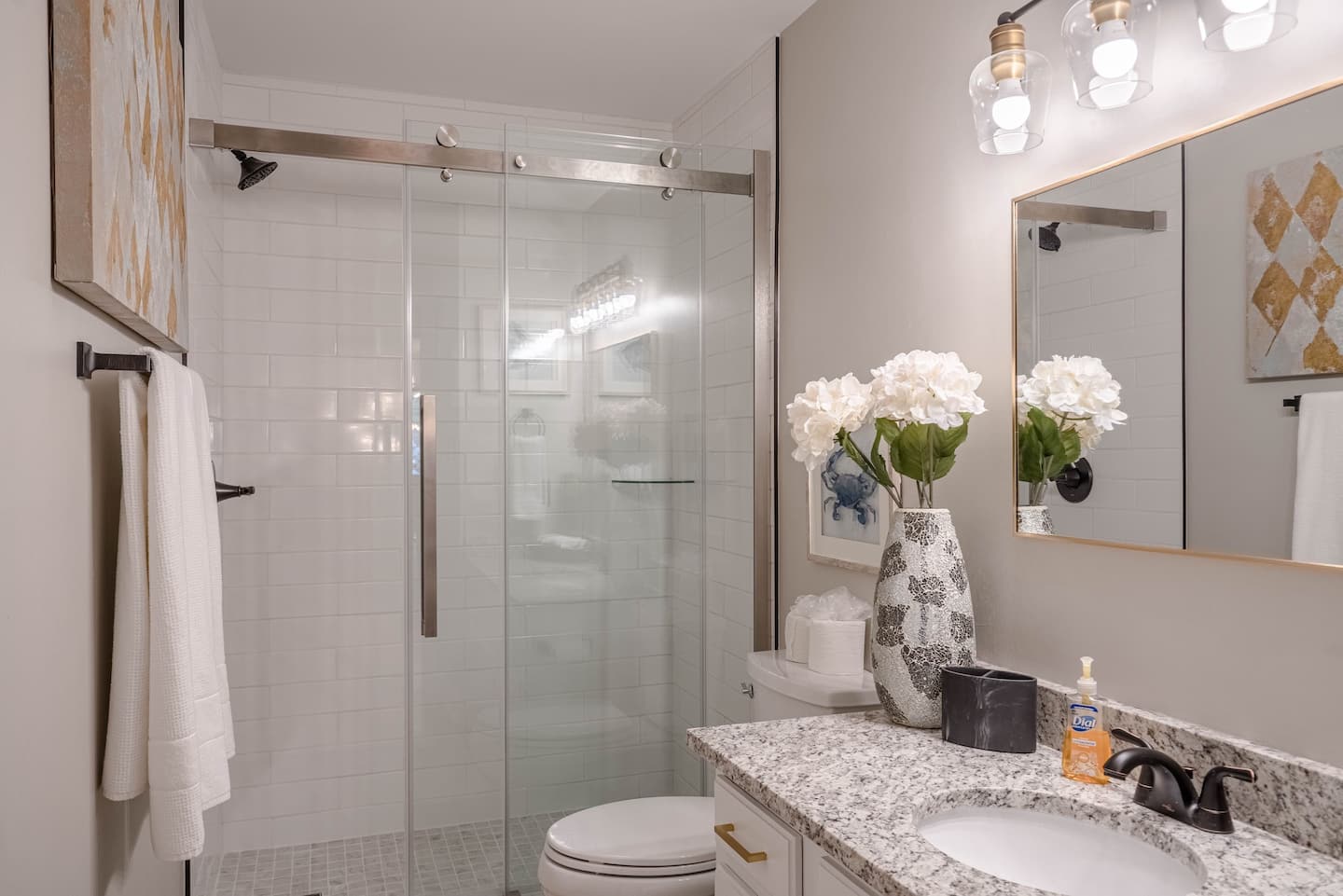 A bathroom with a toilet , sink , mirror and shower.
