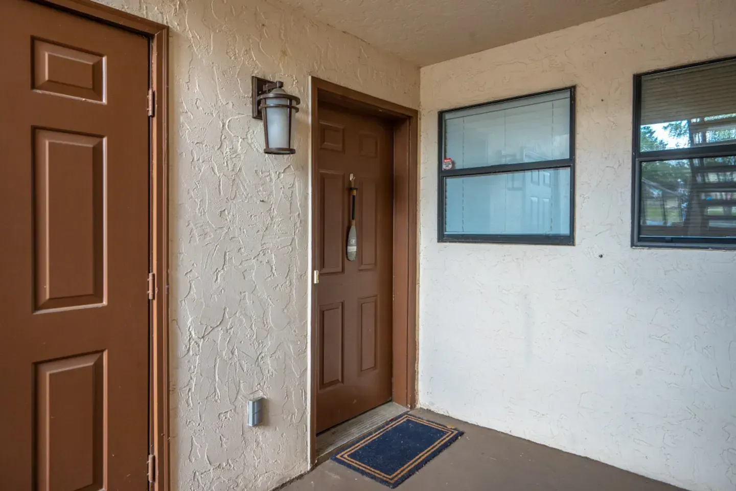 A brown door and a window are on the side of a building.