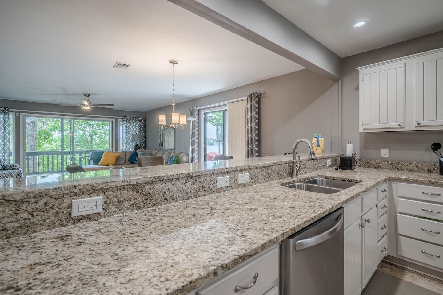 A kitchen with granite counter tops , stainless steel appliances , and white cabinets.