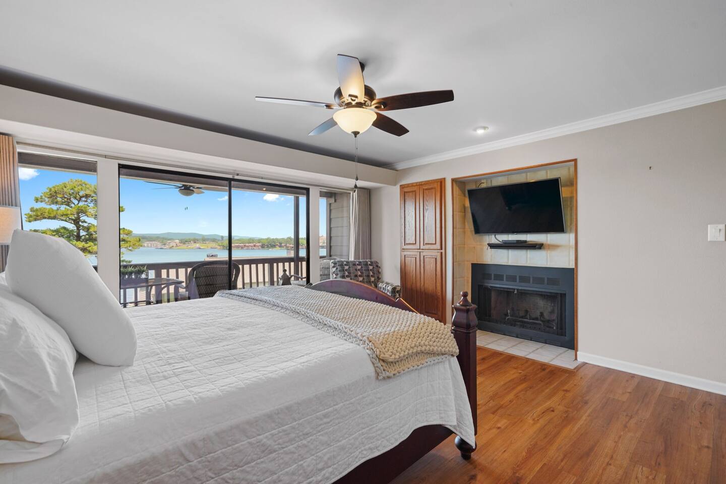 A bedroom with a large bed , ceiling fan , television and fireplace.