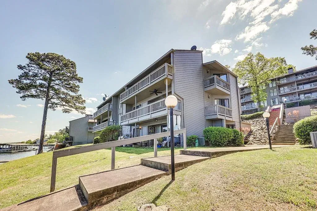 A large building with stairs leading up to it is surrounded by grass and trees.