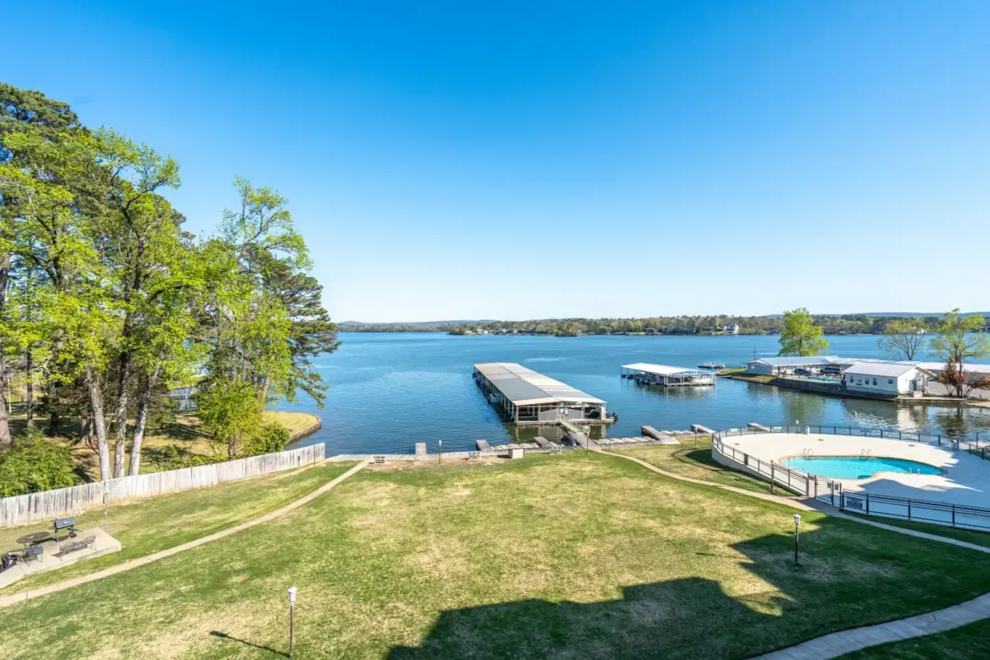 An aerial view of a lake with a dock and a swimming pool.