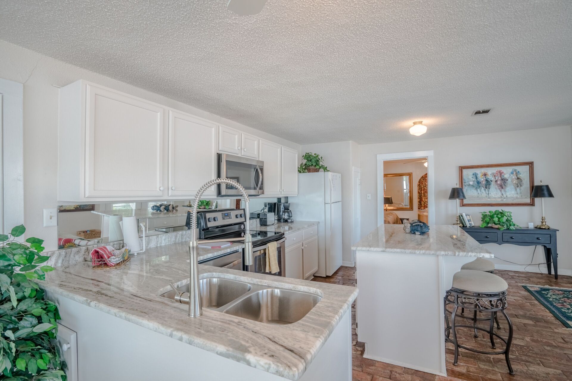 A kitchen with white cabinets , granite counter tops , stainless steel appliances and a sink.