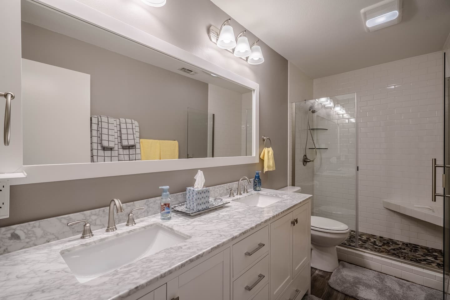 A bathroom with two sinks , a toilet , and a large mirror.