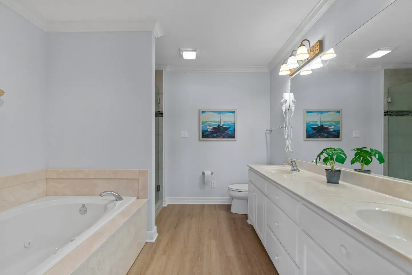 A bathroom with two sinks , a tub , and a large mirror.