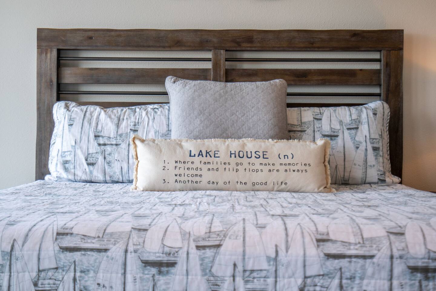 A bed with a pillow that says lake house on it.