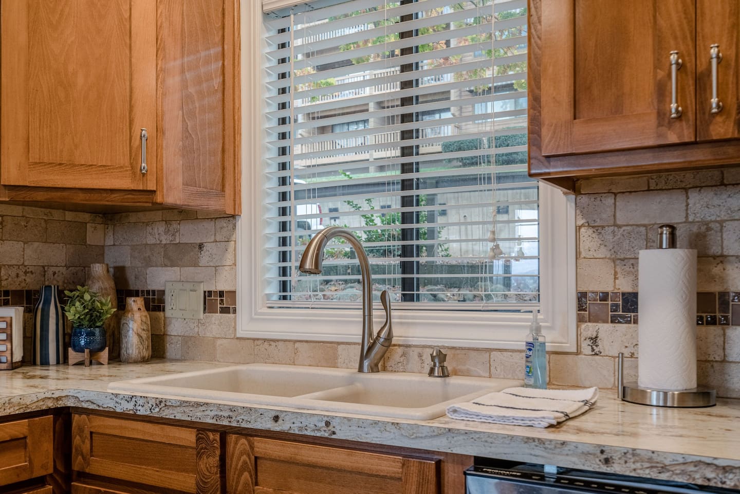 A kitchen with a sink and a window with blinds.
