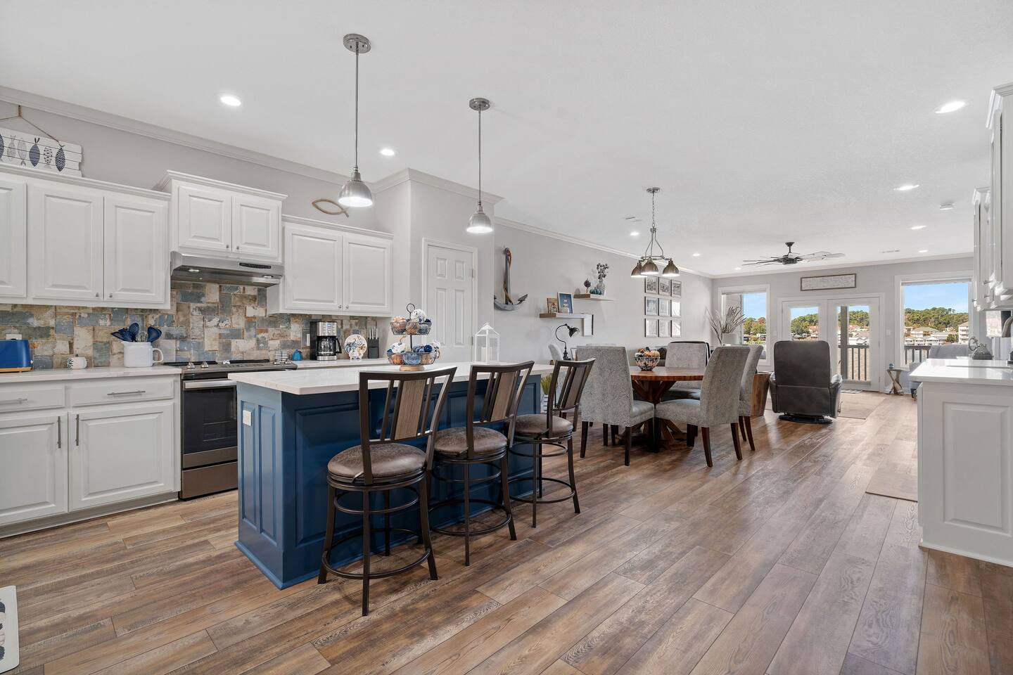 A kitchen and dining room in a house with hardwood floors and white cabinets.