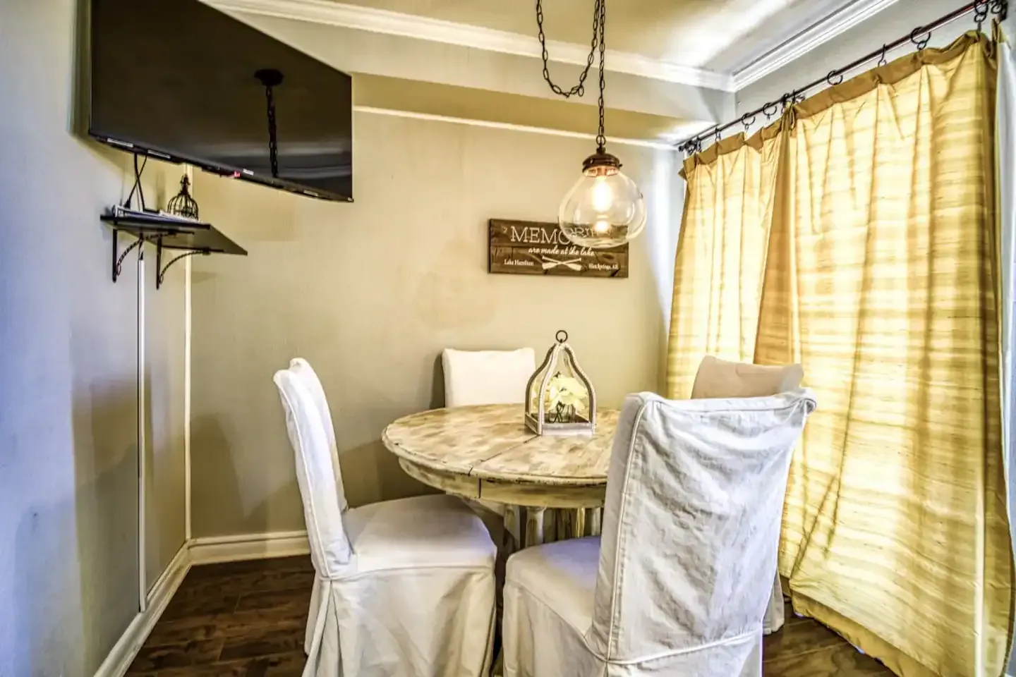 A dining room with a table and chairs and a flat screen tv.