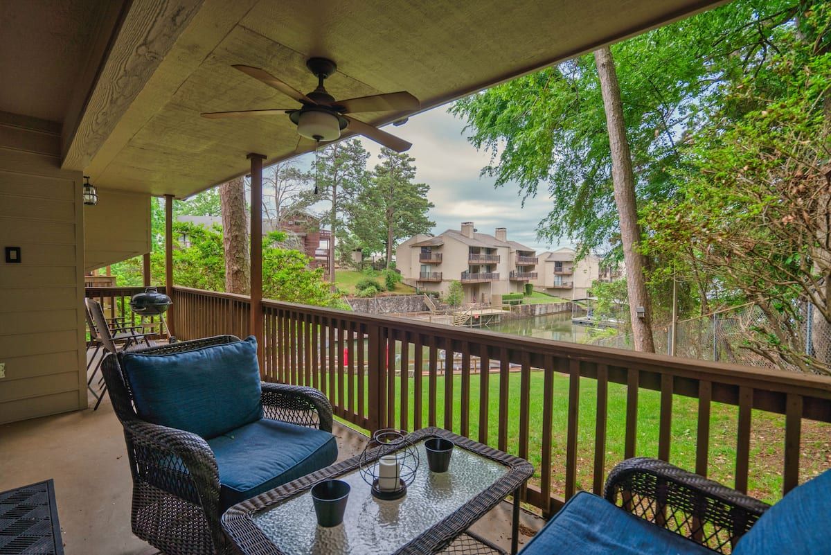 A balcony with chairs , a table and a ceiling fan.