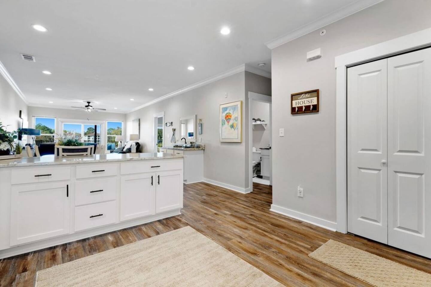 A kitchen with white cabinets and hardwood floors in a house.