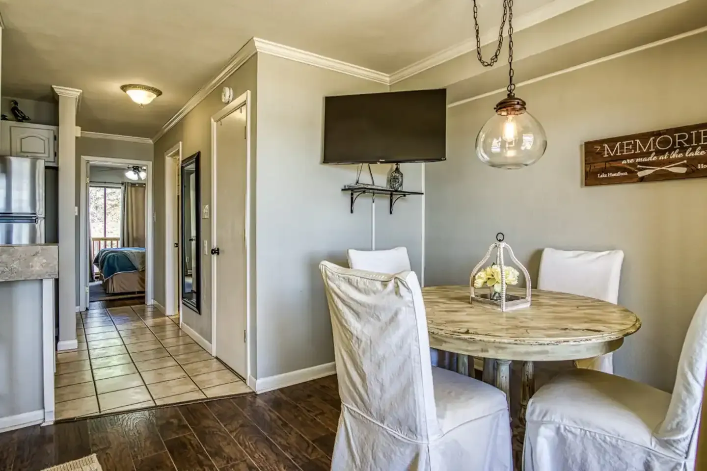 A dining room with a table and chairs and a flat screen tv.