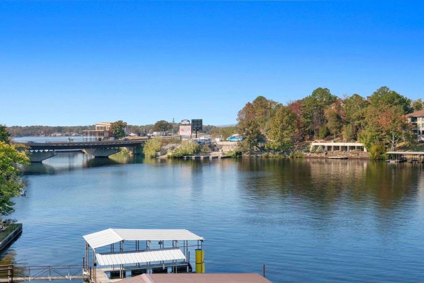 A large body of water with a bridge in the background and a dock in the foreground.