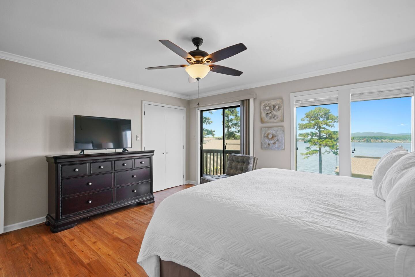 A bedroom with a bed , dresser , television and ceiling fan.