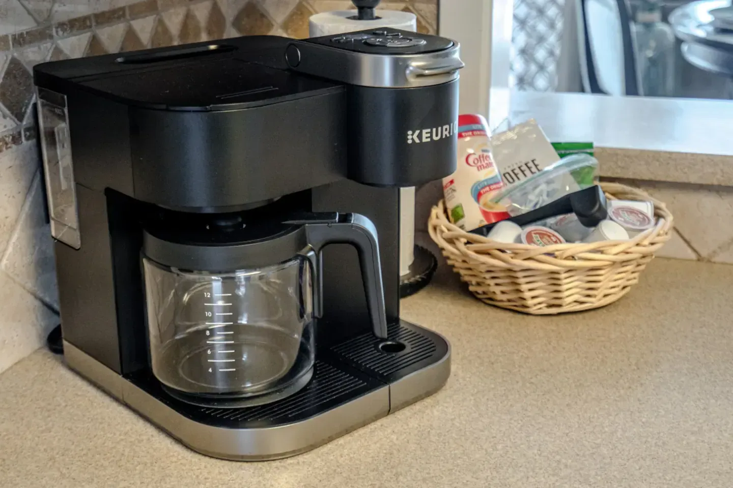 A keurig coffee maker is sitting on a counter next to a basket of food.