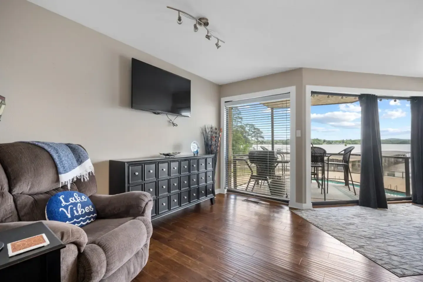 A living room with a couch , chair , television and sliding glass doors.