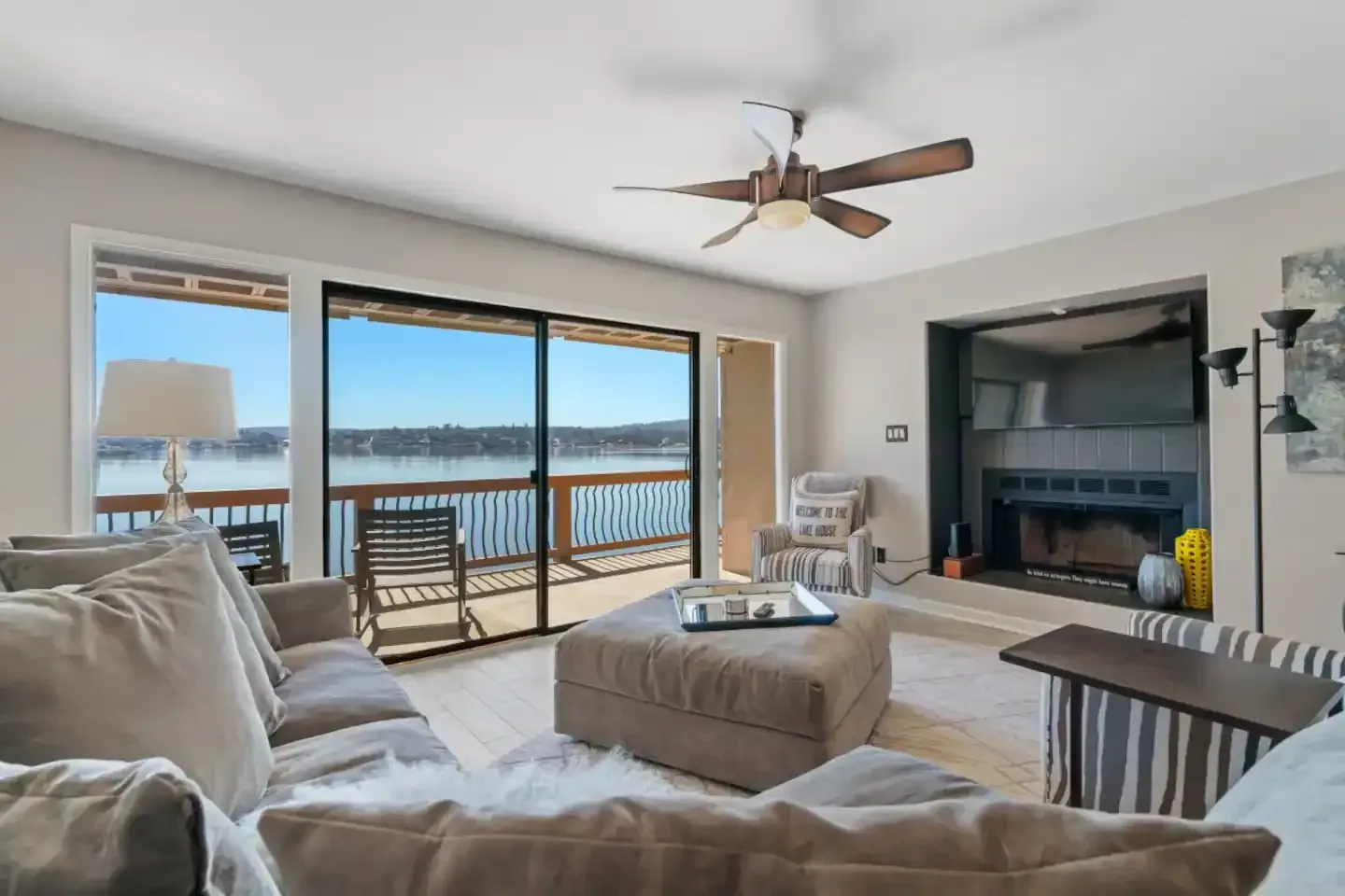 A living room with a couch , ottoman , fireplace and ceiling fan.